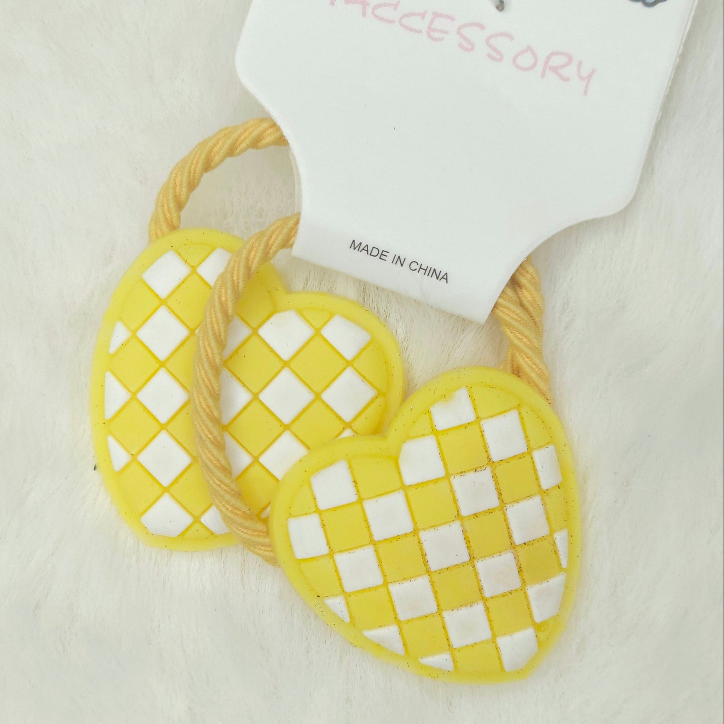 Yellow heart-shaped hair ties with a checkered pattern on a white background