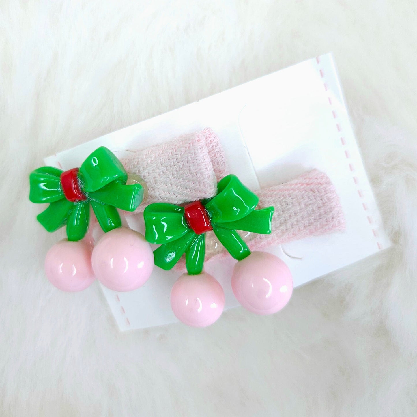Pair of pink hair clips with green bows on a white background