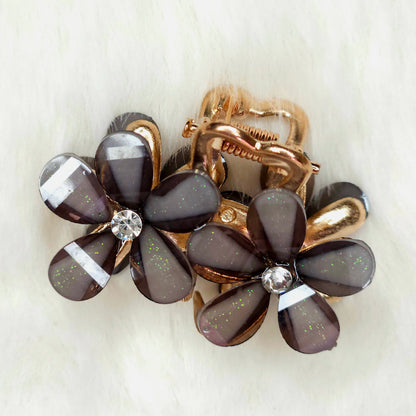 Floral hair clip with brown petals and gold accents on a white background