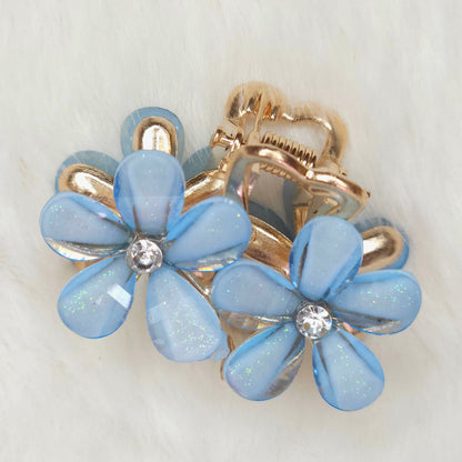 A blue flower-shaped hair clips with gold accents on a light gray background