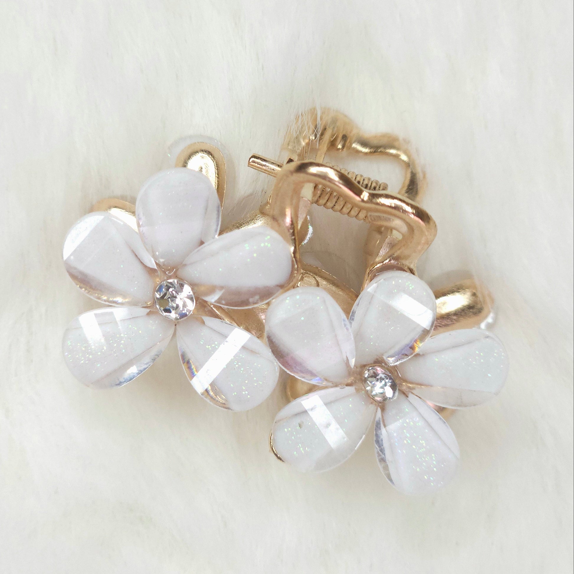 White flower-shaped hair clip with gold accents on a light background
