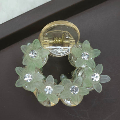 Close-up of a small, mint green flower grip clip with translucent green petals and tiny, clear rhinestones set into the circular frame.