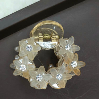 Top-down view of a peach-colored micro hair clip decorated with floral-cut resin pieces and small, inlaid rhinestones for a soft sparkle.