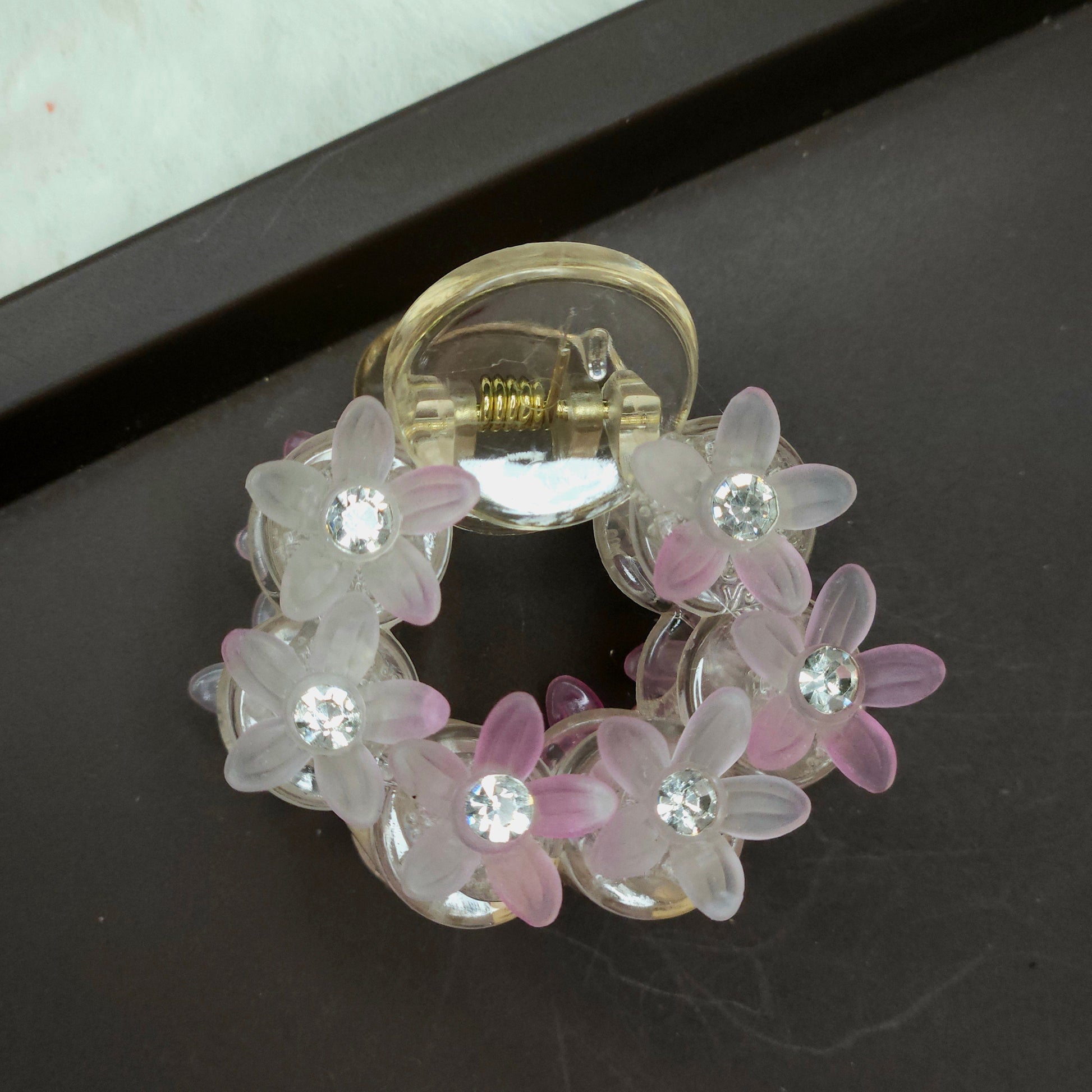 Small, light pink floral hair claw with shimmering translucent resin beads shaped like flowers and subtle sparkle from embedded rhinestones.