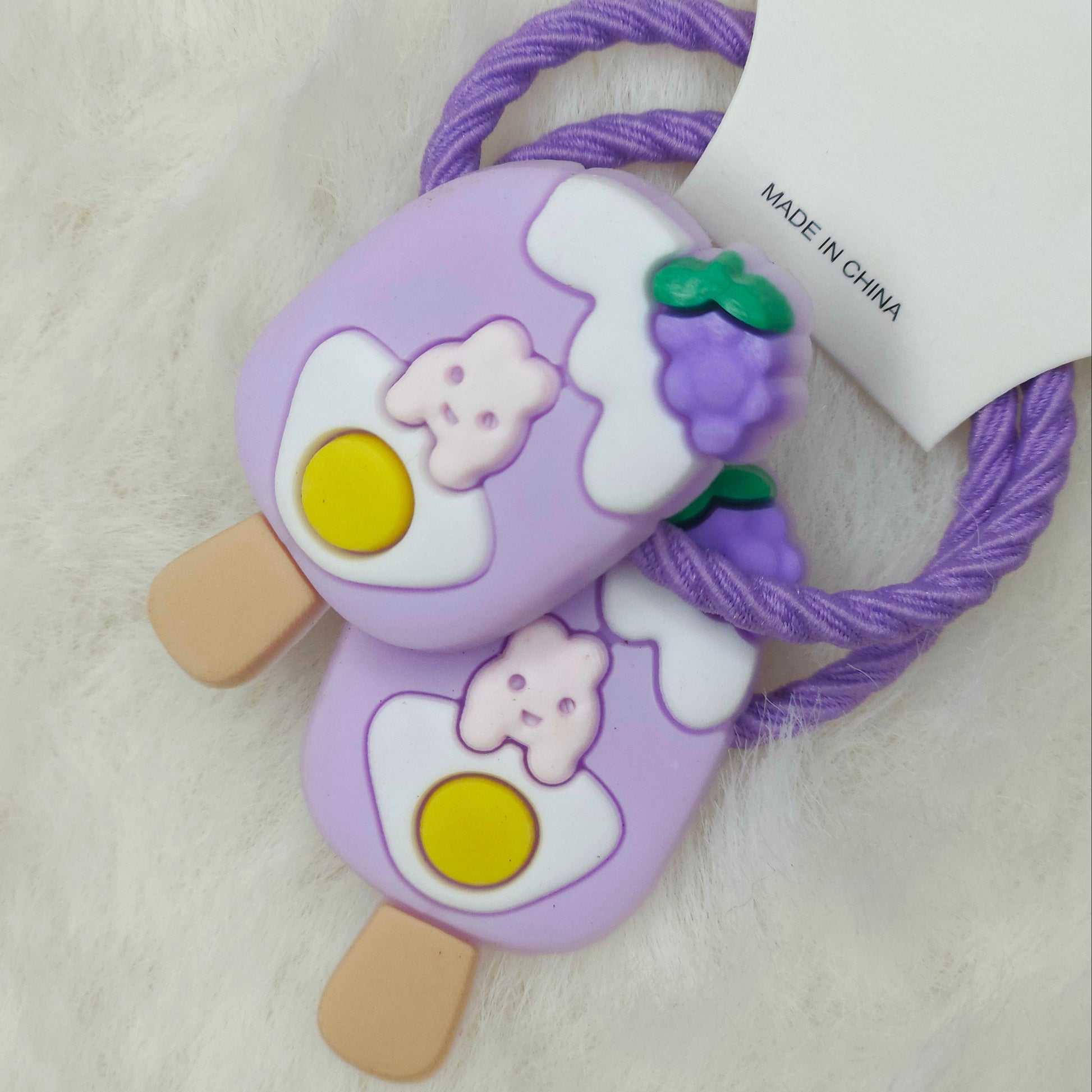 Purple ice cream-shaped hair ties with cartoon characters on a white background
