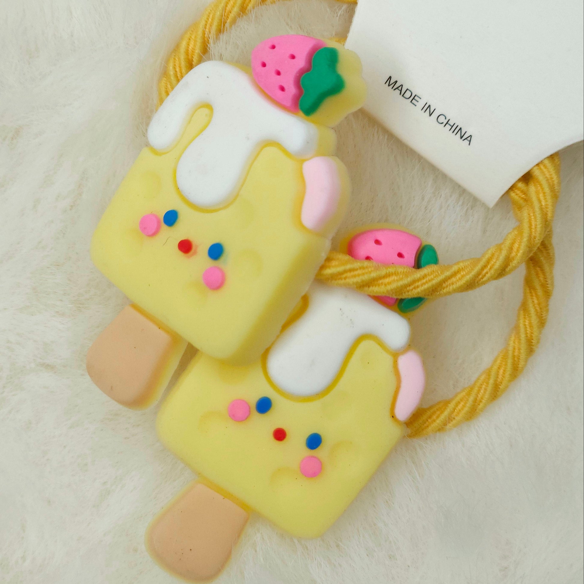 Hair tie designed like a ice cream popsicle with colorful decorations on a light background