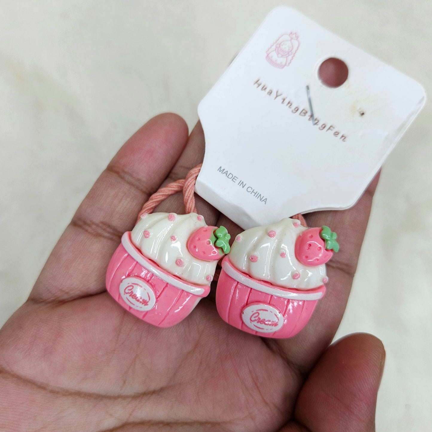 Pink and white hair ties with a 'Made in China' label on a beige background