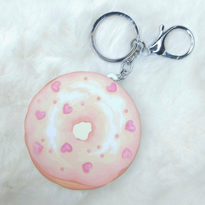 Donut-shaped keychain with pink glaze and heart sprinkles on a white background