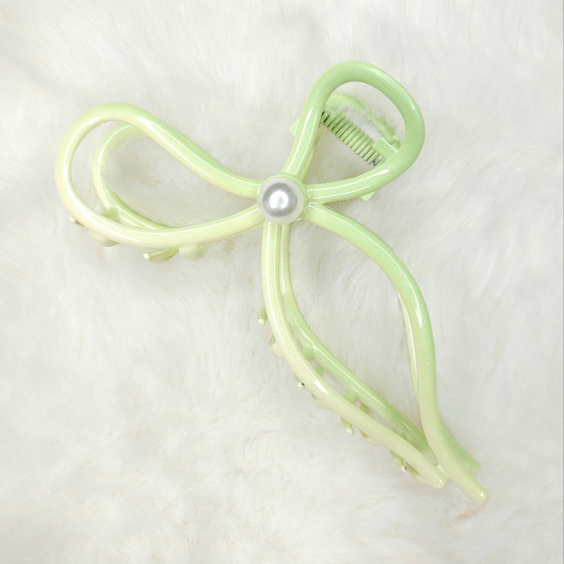 Light green bow-shaped hair clip with a pearl on a white background