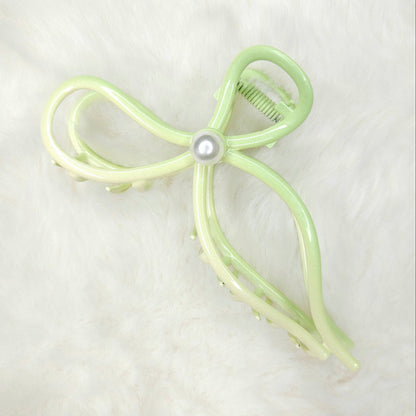 Light green bow-shaped hair clip with a pearl on a white background