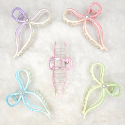 Set of five pastel-colored butterfly-shaped hair clips on a light gray background