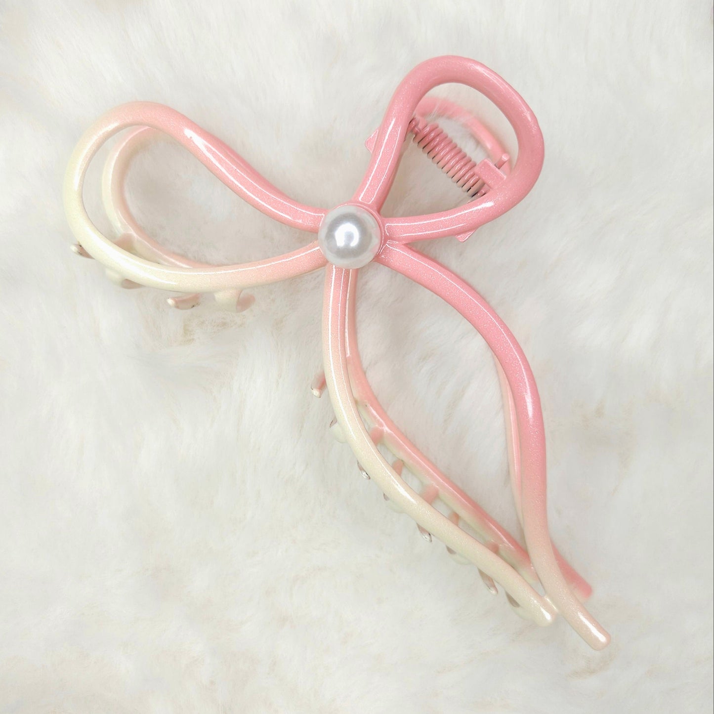 Pink and white bow-shaped hair clip on a light background