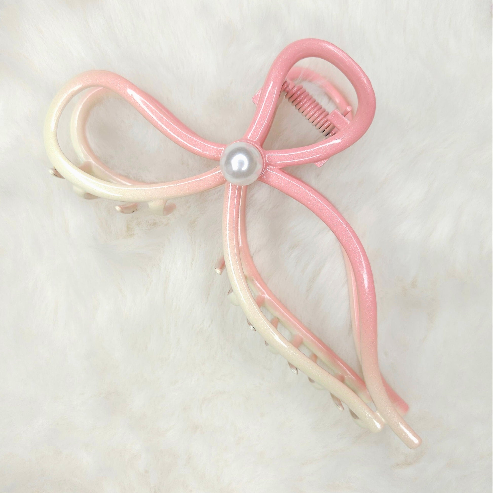 Pink and white bow-shaped hair clip on a light background