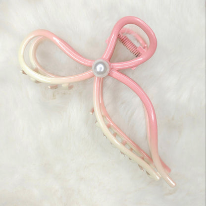Pink and white bow-shaped hair clip on a light background