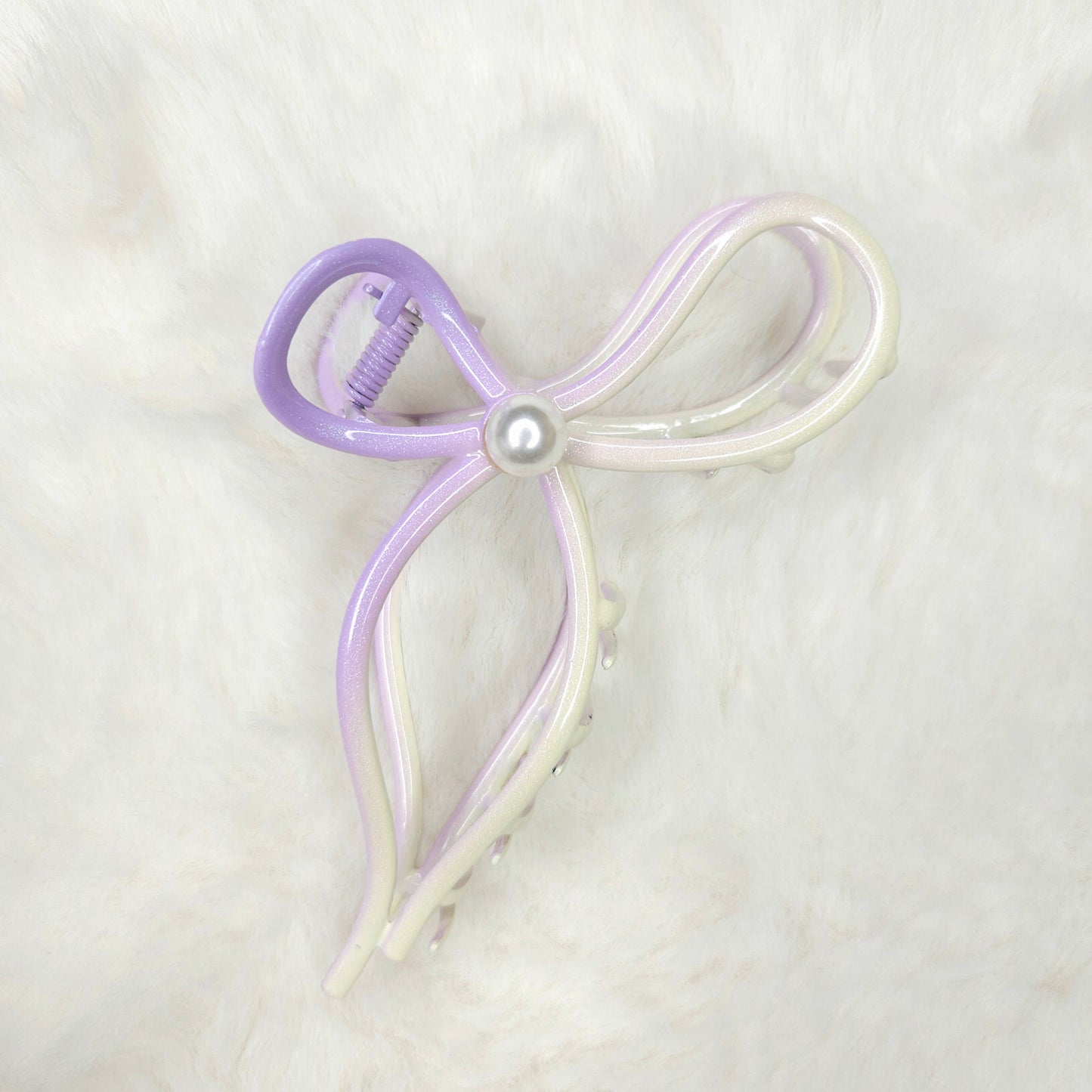 Bow-shaped hair clip with a pearl center on a light background