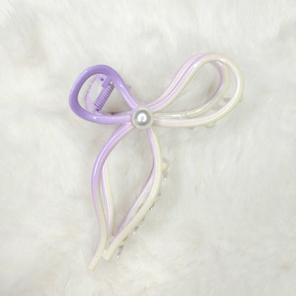 Bow-shaped hair clip with a pearl center on a light background