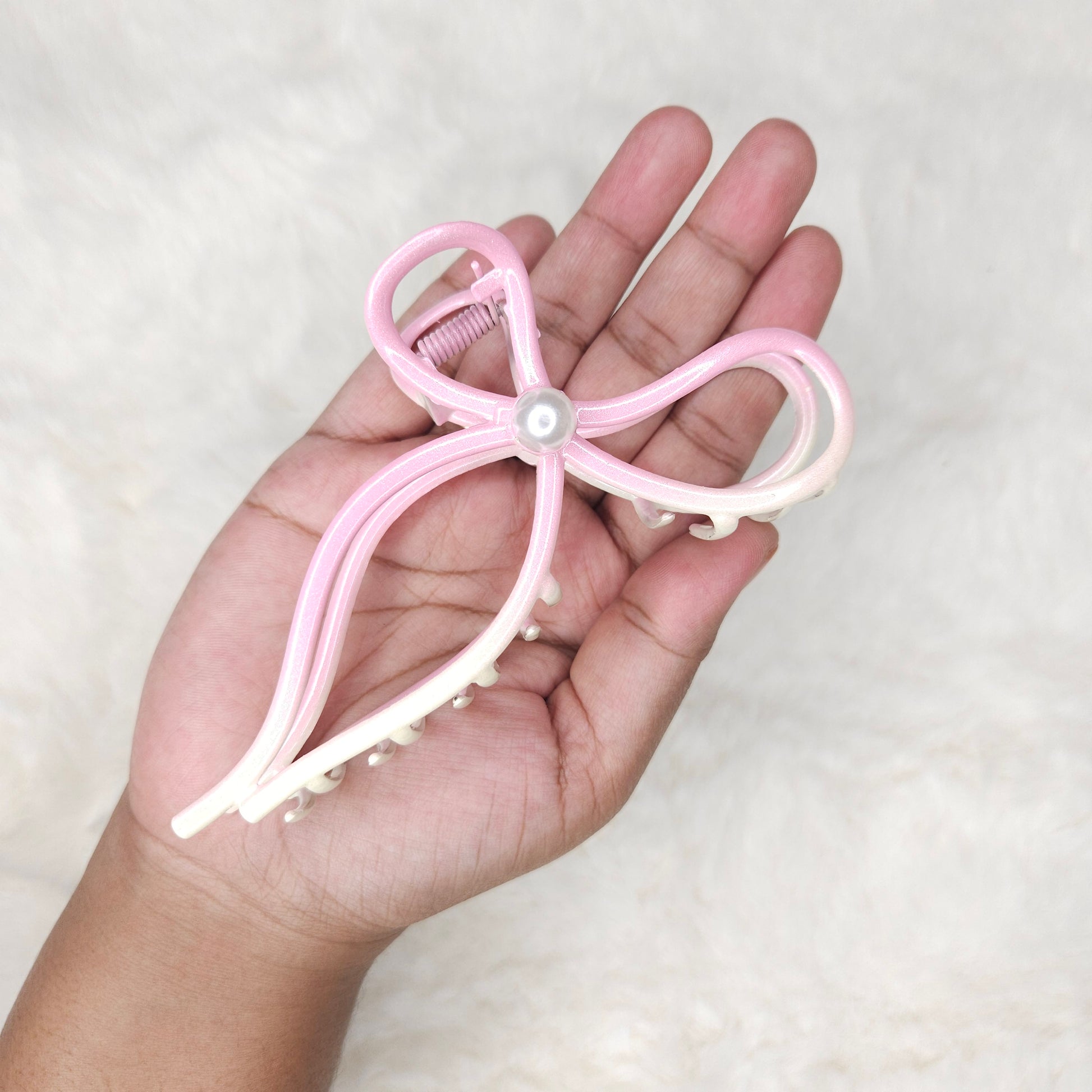 Hand holding a pink hair claw against a white background