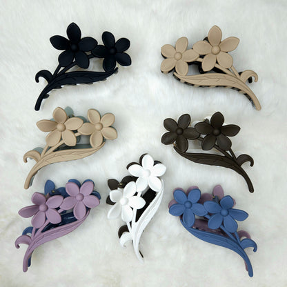 Set of seven floral-shaped hair claw clips in various colors on a white background
