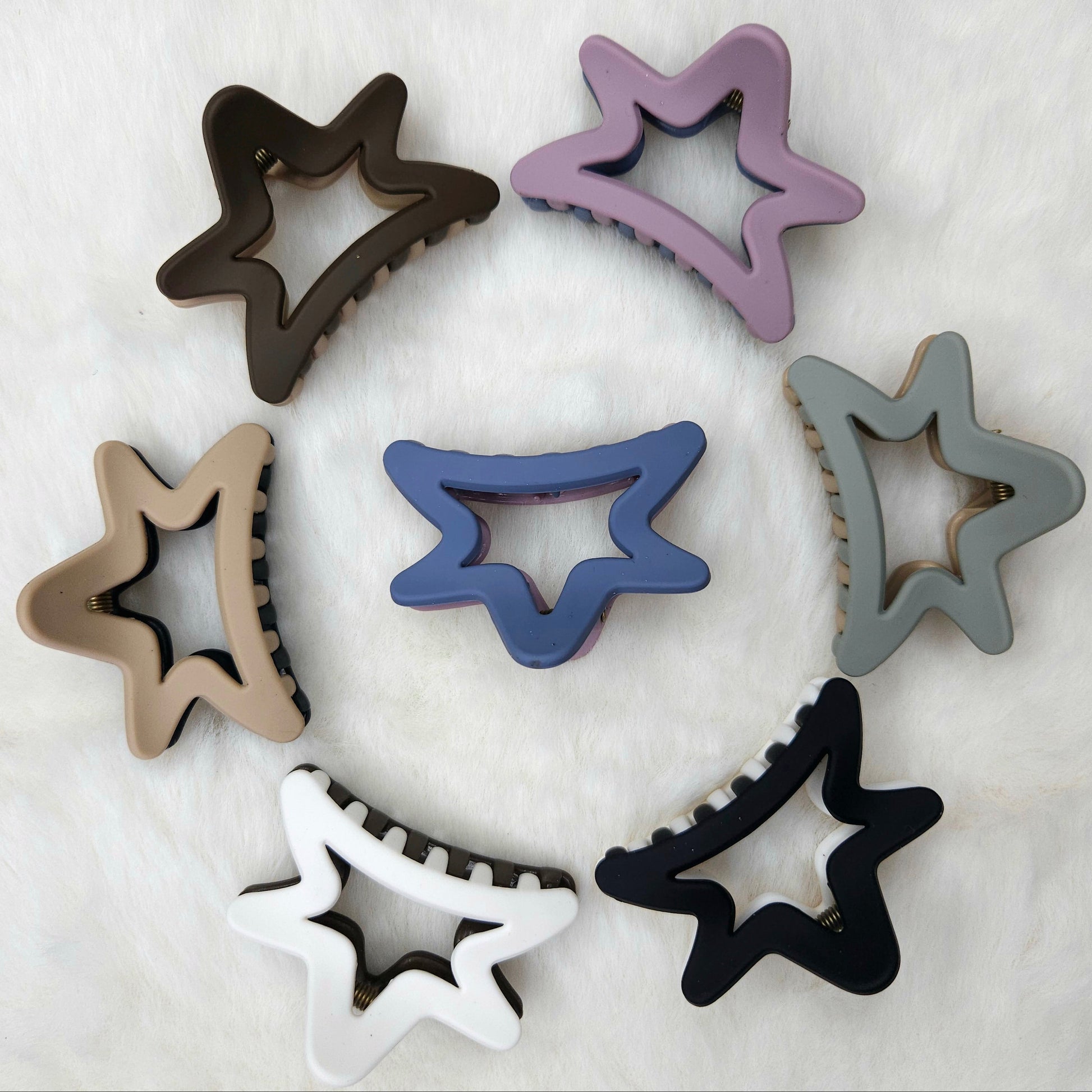 Semi Star-shaped hair claw clips in various colors arranged in a circular pattern on a white background.