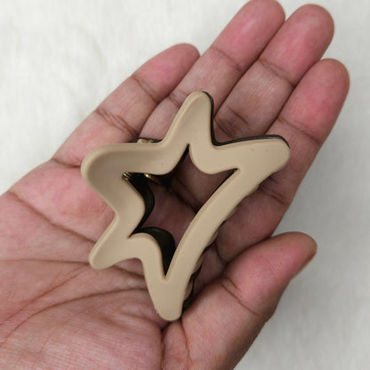 Hand holding two beige star-shaped hair claw against a white background