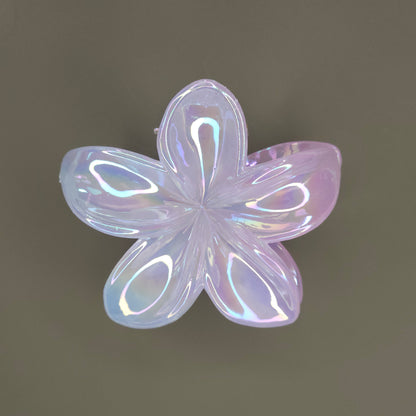 A medium-sized, flower-shaped hair claw clip made of a white material with a 'dual shade glimmer' finish, creating subtle iridescent shifts or a pearlescent effect, possibly hinting at soft pastel undertones.