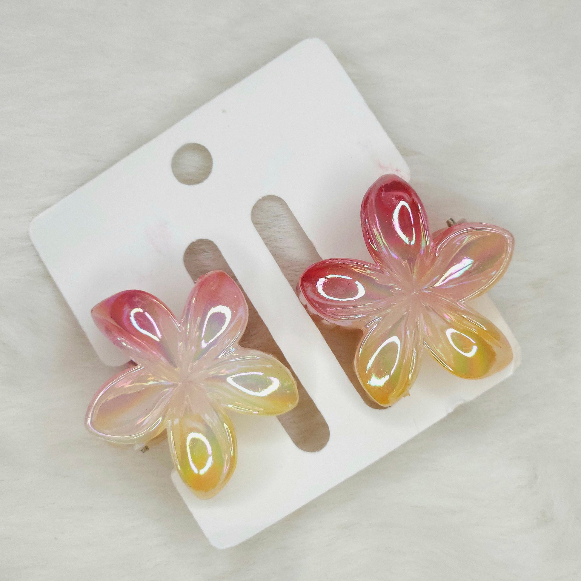 Detailed close-up of red-yellow shared flower hair claw in rose color, showing dual-shade floral pattern.