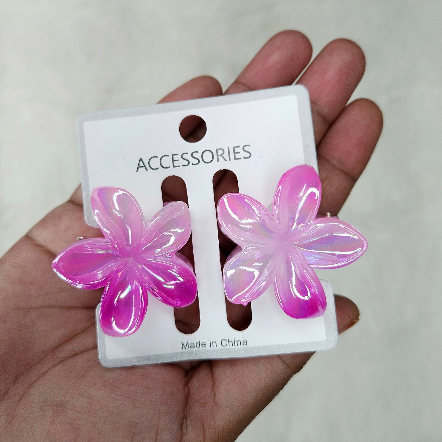 Flower-shaped mini hair claw in rose colour held for size reference