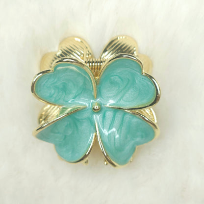 Turquoise flower-shaped hair claw with gold outline on a white background