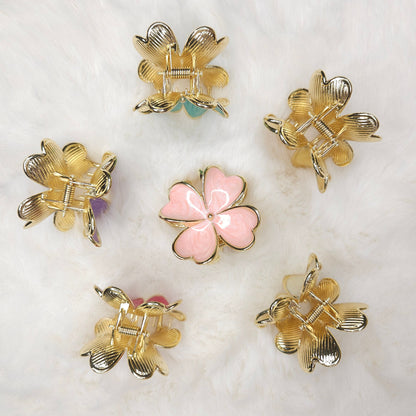 Gold and pink hair clips on a white marble surface