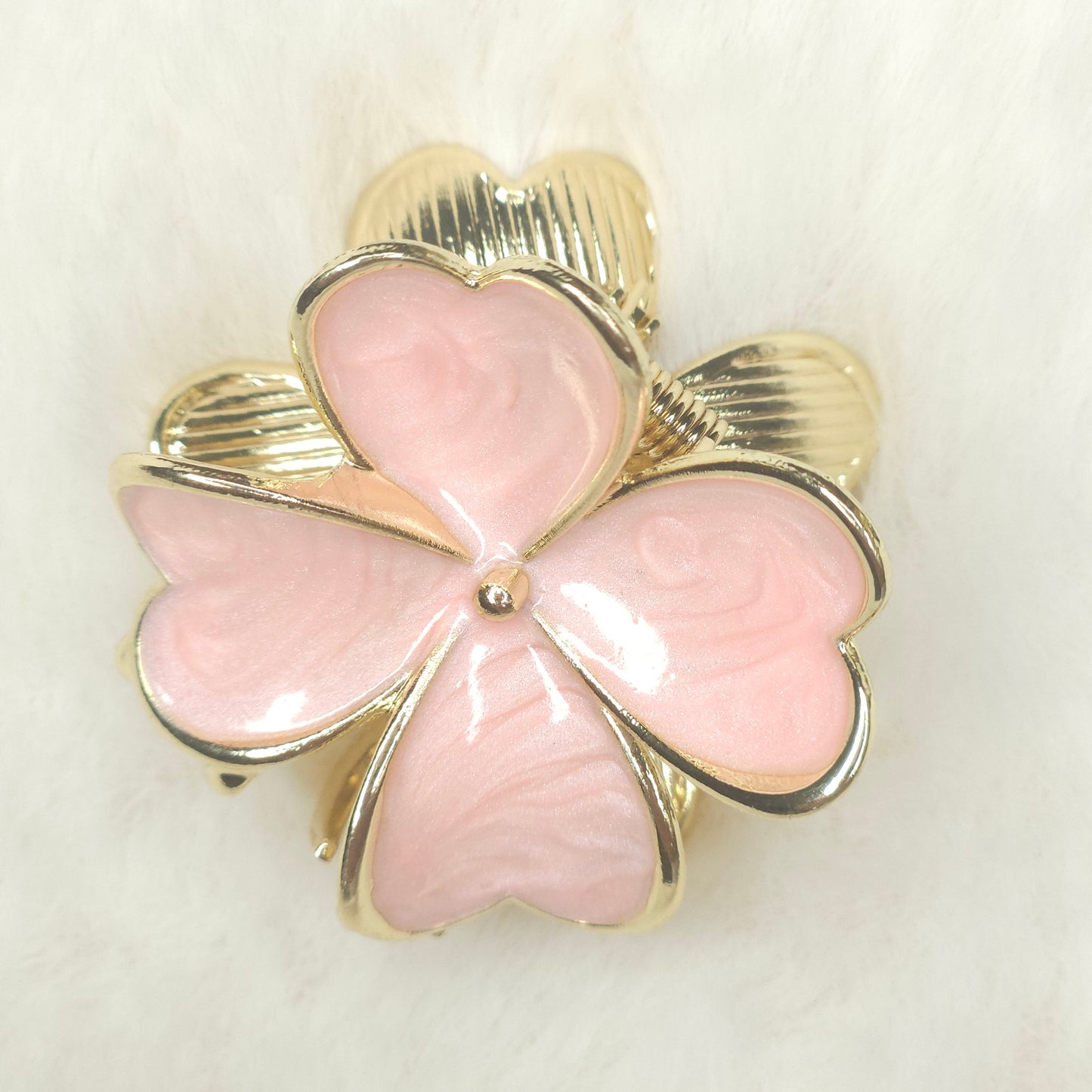Pink clover-shaped hair claw with gold detailing on a white background