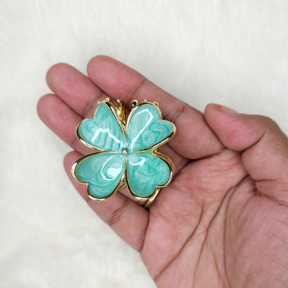 Turquoise butterfly-shaped hair claw held in a hand against a white background