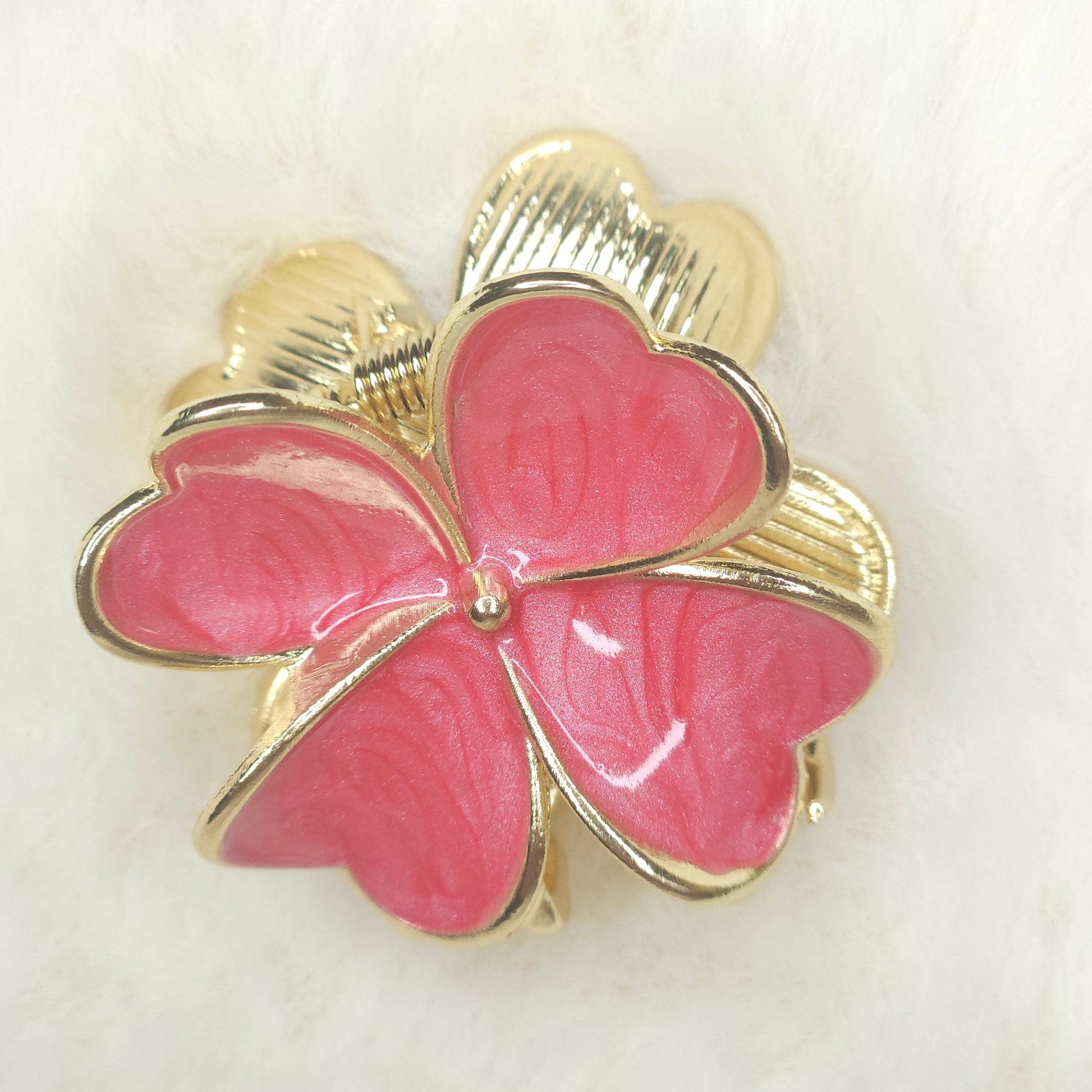 Pink flower-shaped hair claw with gold accents on a white background