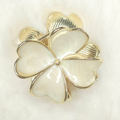 Gold and white four-leaf clover brooch on a light background