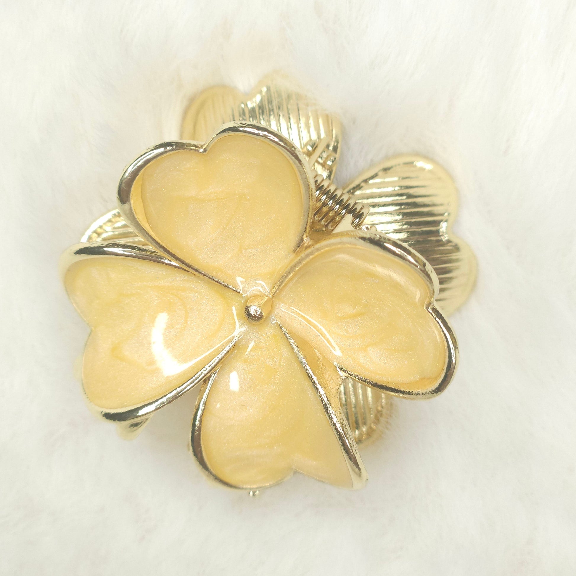 Clover-shaped hair claw with gold and silver details on a white background