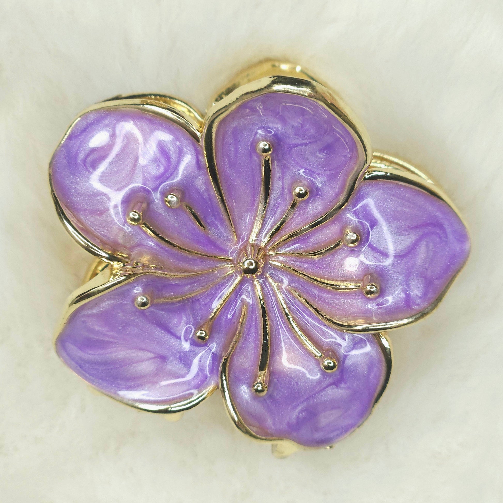 Purple flower-shaped hair claw with gold detailing on a light background