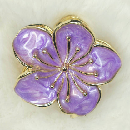 Purple flower-shaped hair claw with gold detailing on a light background