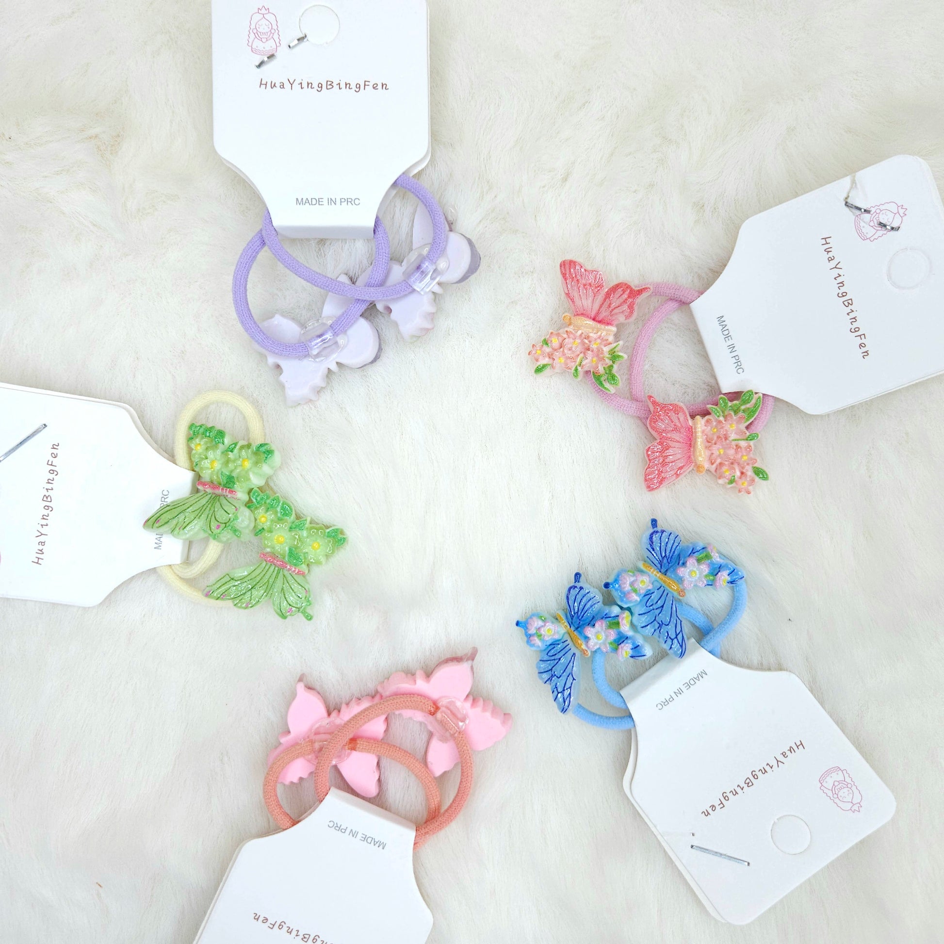 Colorful butterfly-shaped hair ties on a white surface with visible brand tags.