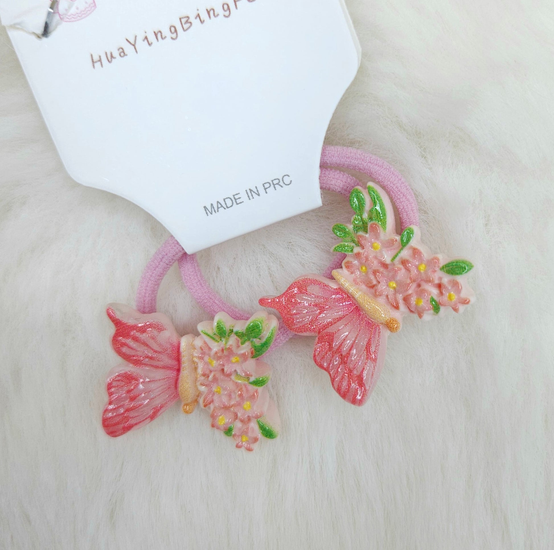Pink hair ties with butterfly and flower designs on a white background