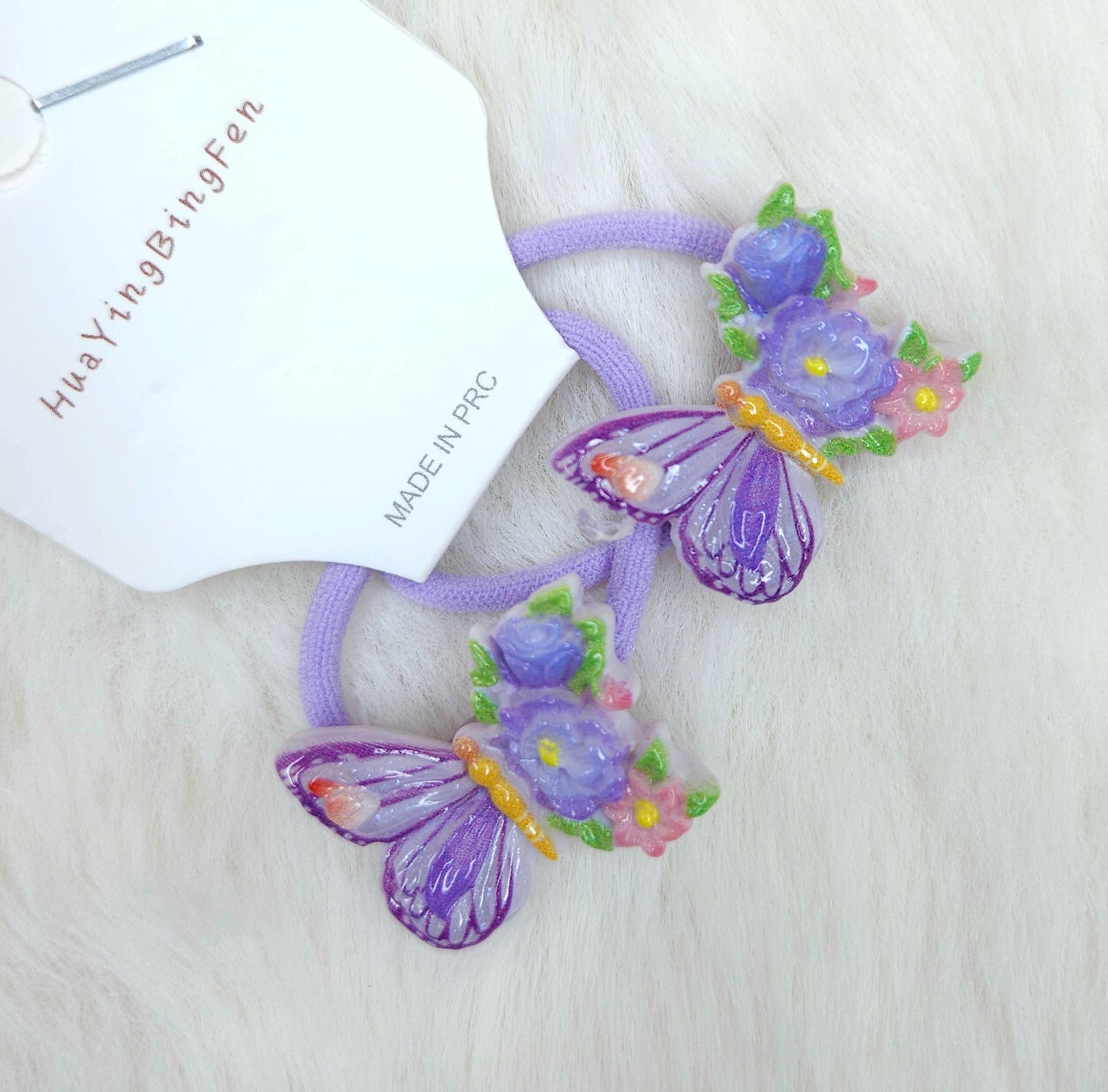 Purple butterfly hair ties with flowers on a white background