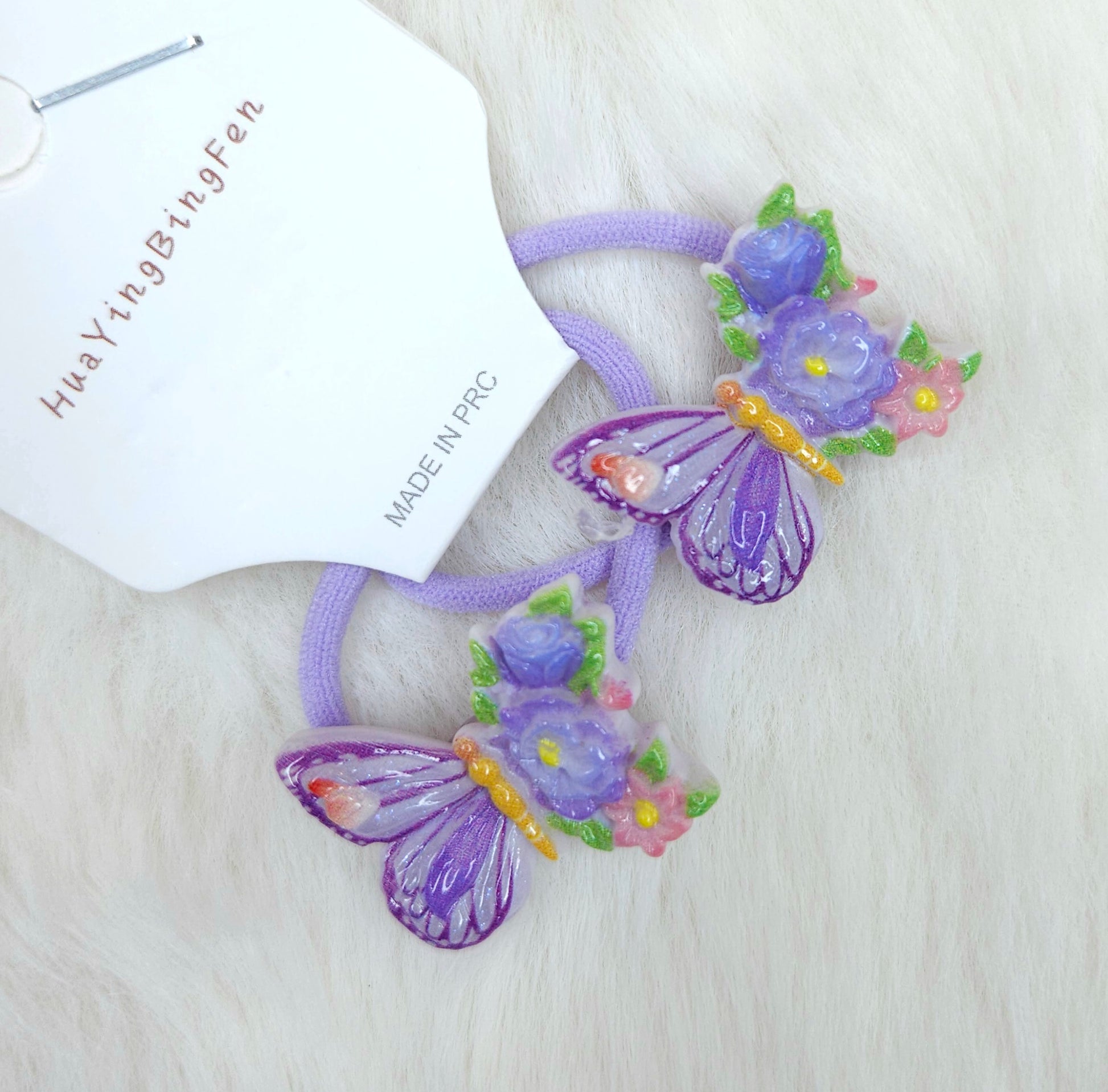 Purple butterfly hair ties with flowers on a white background