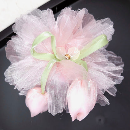Decorative flower accessory with pink petals and white tulle on a black surface