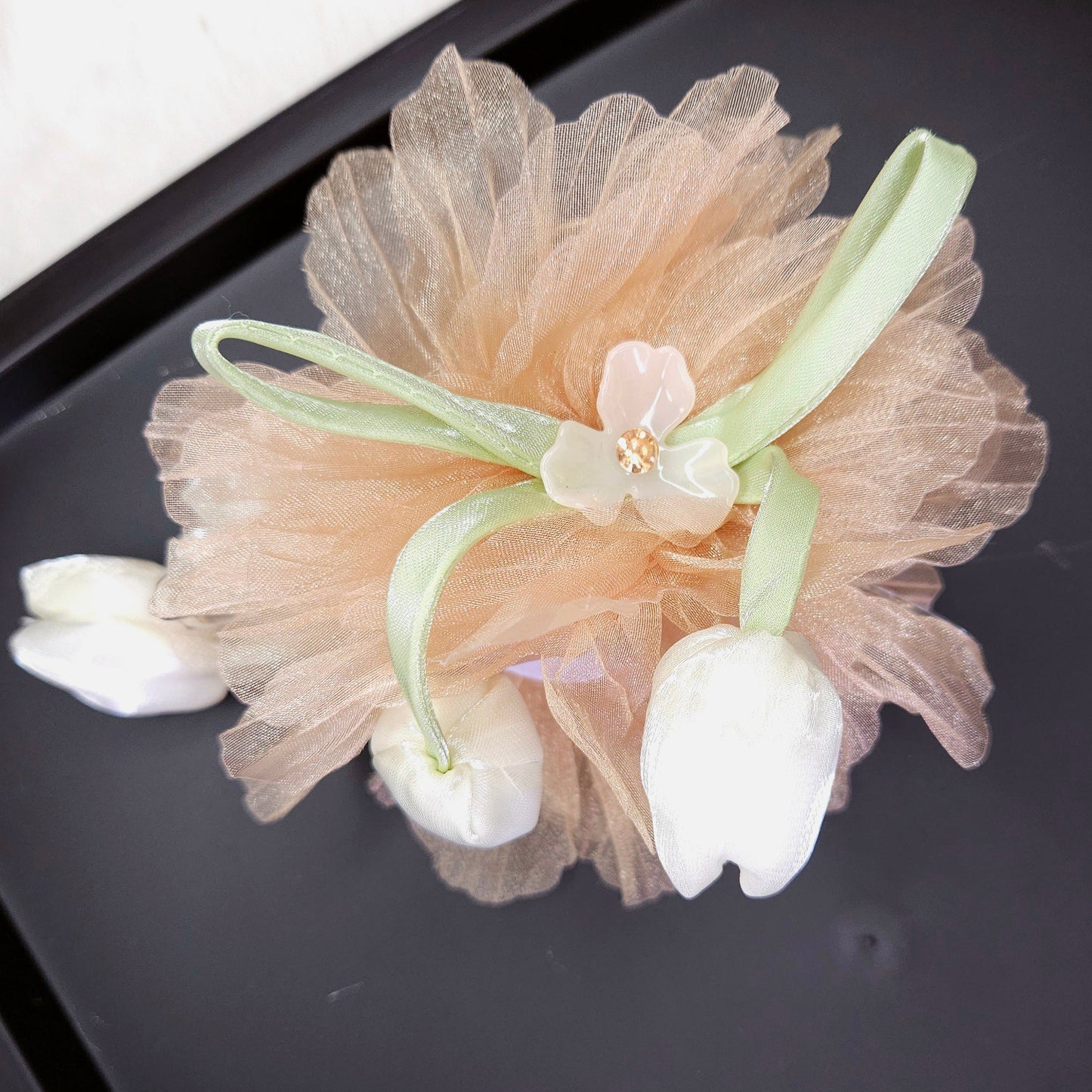 Decorative hair clip with floral elements on a black surface