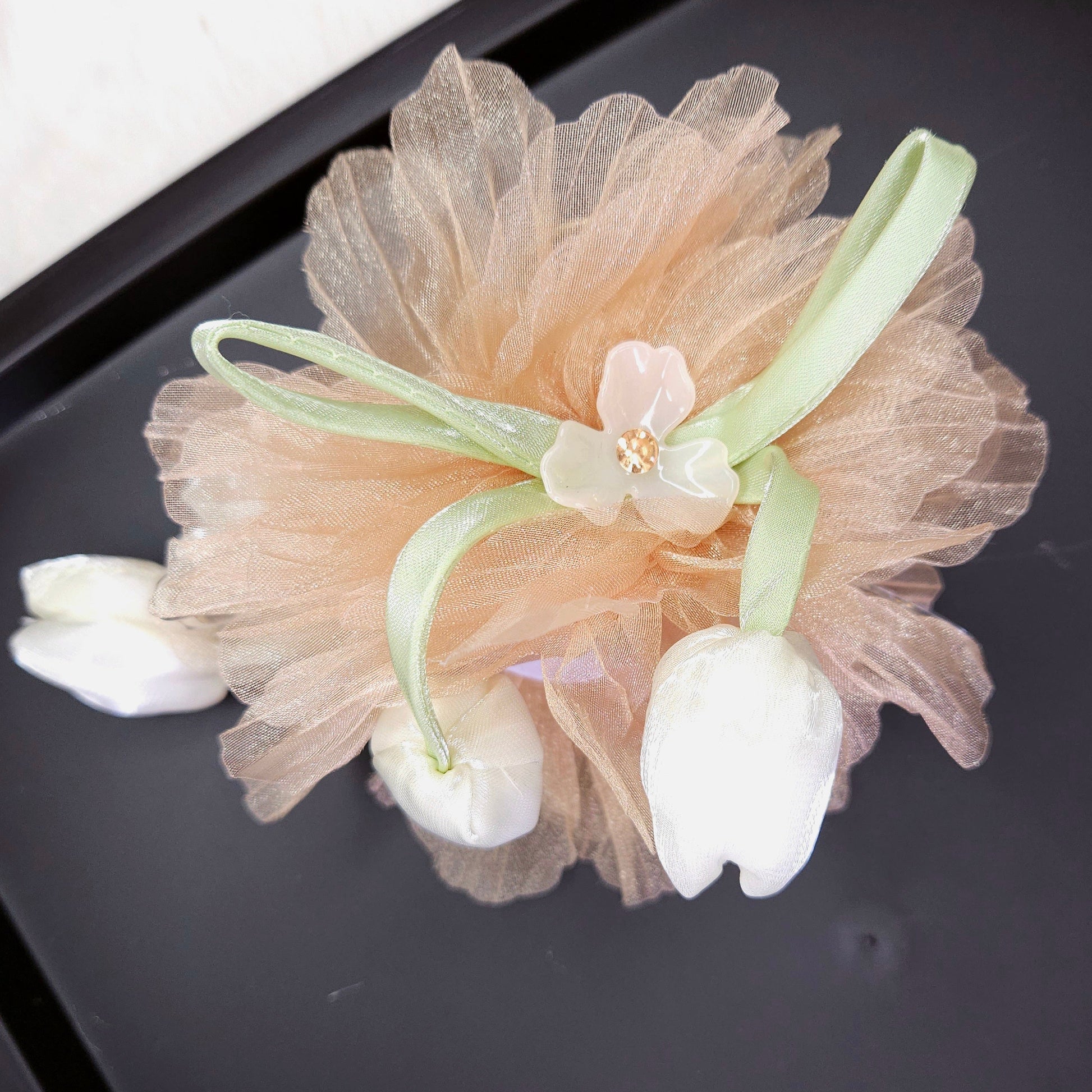 Decorative hair clip with floral elements on a black surface