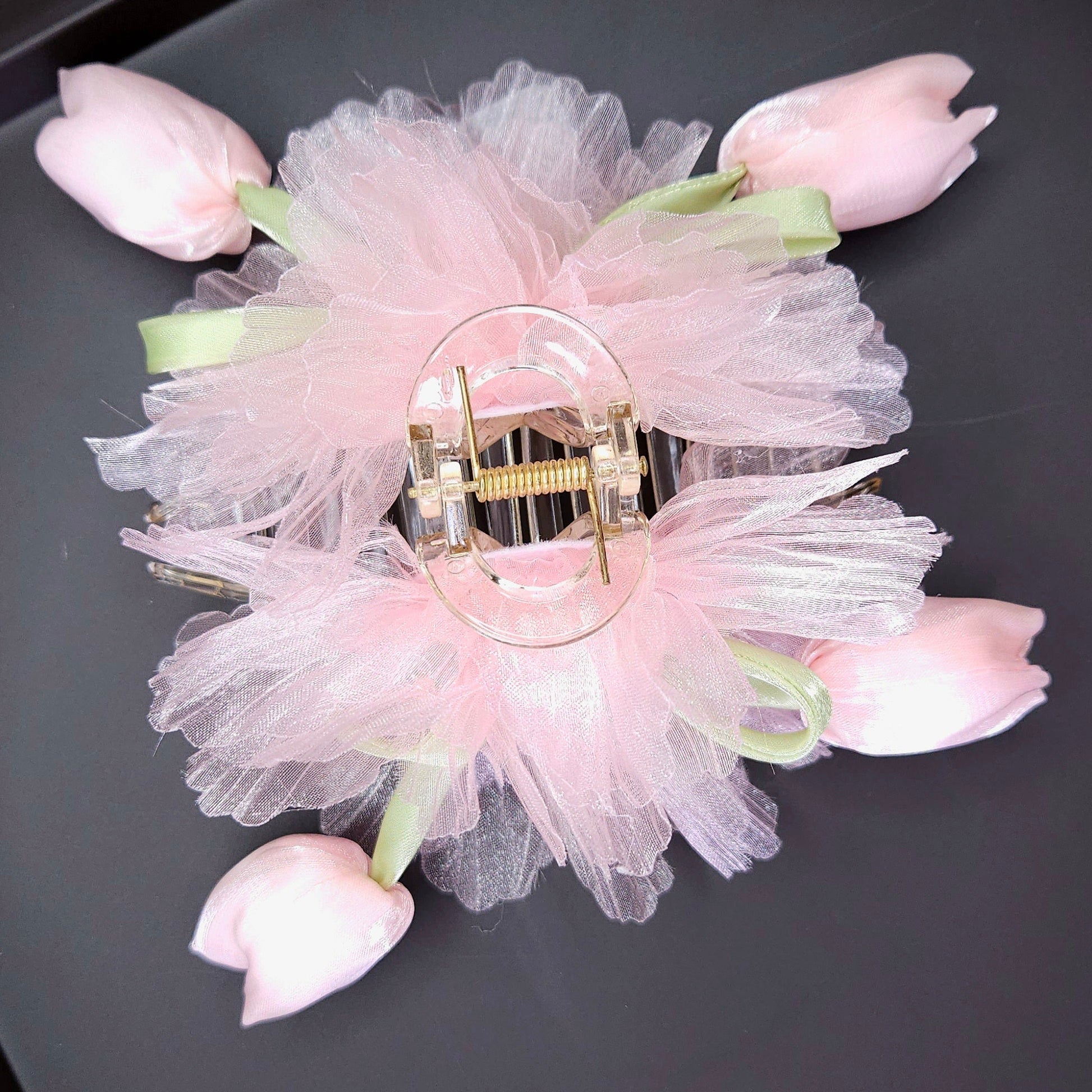 Decorative hair clip with pink flowers on a black tray