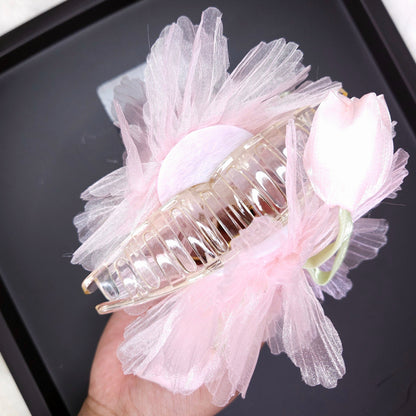Hair clip with pink tulle and flowers on a black tray