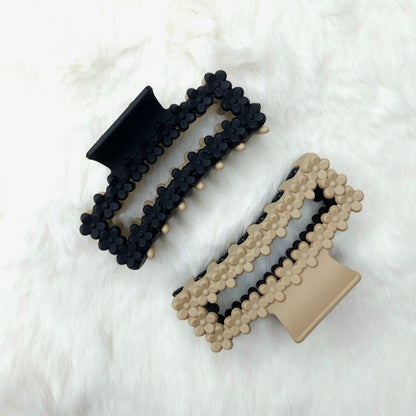 Two dual tone hair claw clips, one side black and one side beige, on a white background