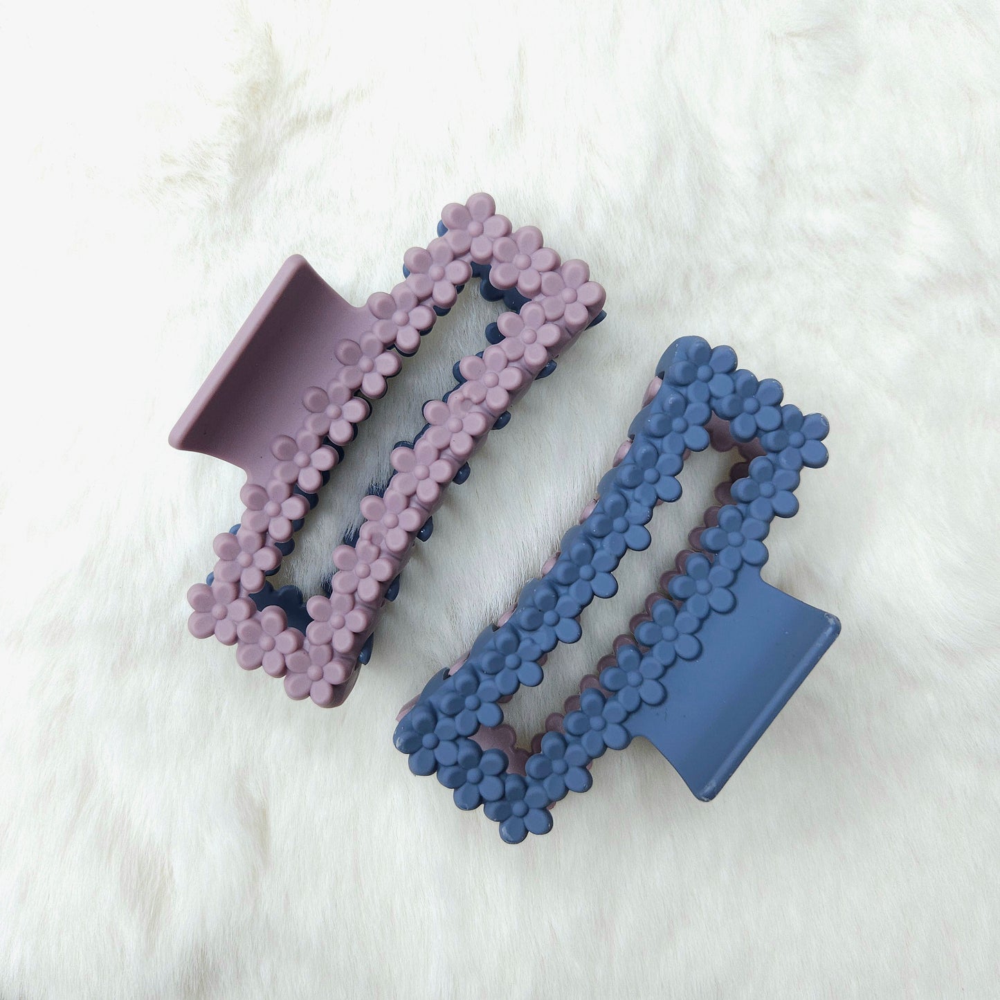 Two rectangular shaped hair claw clips, one side purple and one side blue, on a white background