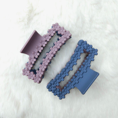 Two rectangular shaped hair claw clips, one side purple and one side blue, on a white background