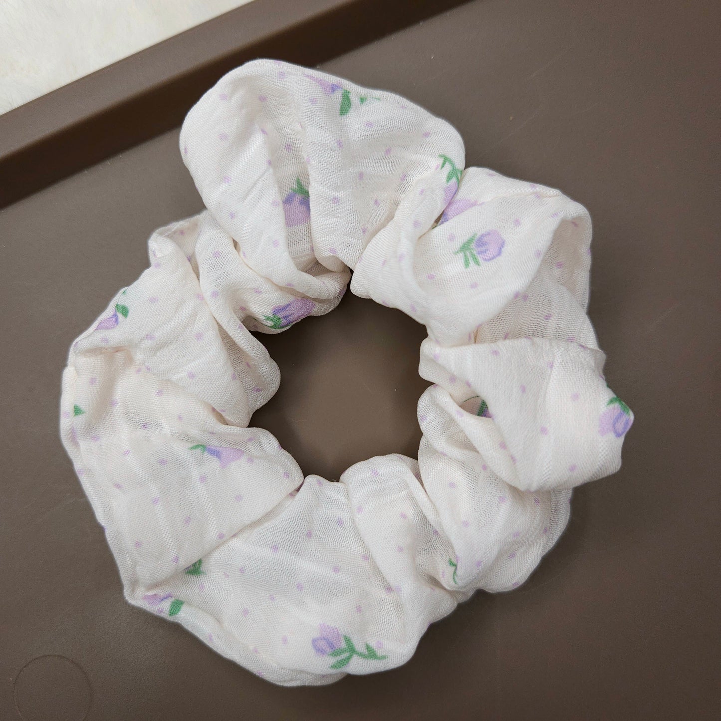 White scrunchie with floral pattern on a brown surface