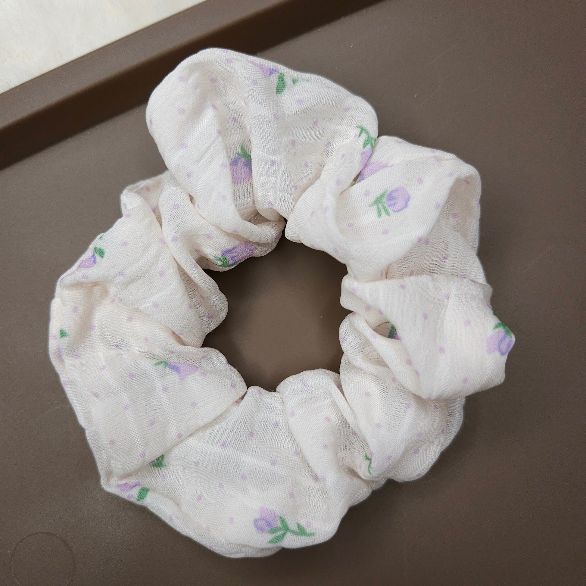 White scrunchie with floral pattern on a brown surface